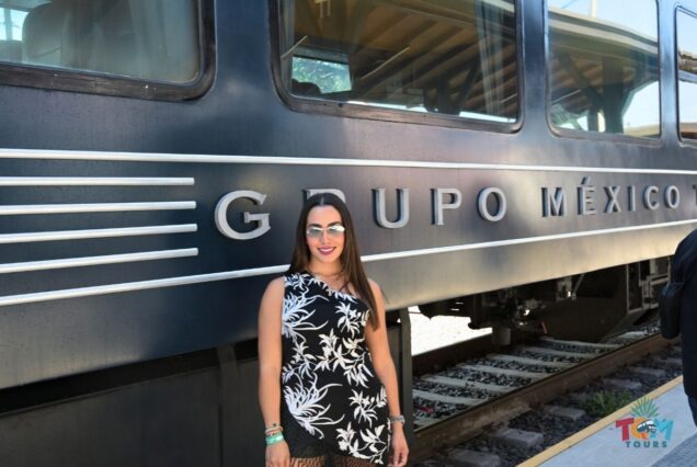 A woman standing in front of the Grupo México Transportes Tequila Express train during a TQM Tours excursion.
