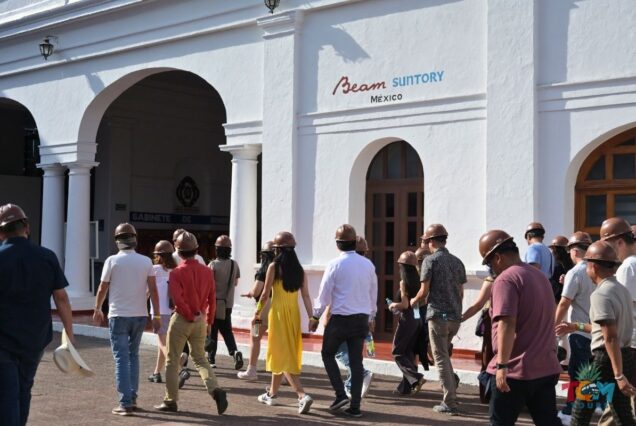 Visitors wearing hard hats walk across the courtyard toward the Beam Suntory Mexico building.