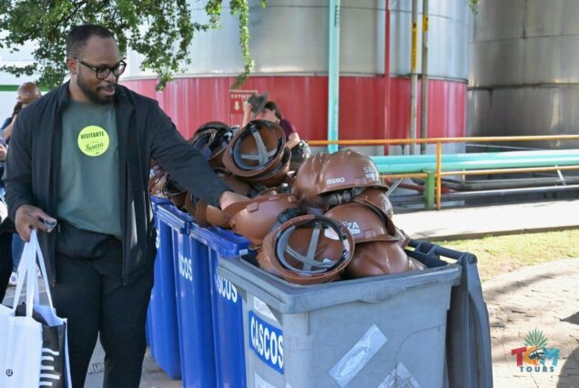 Man returning brown hard hats to a large container labeled “Cascos” at Casa Sauza.