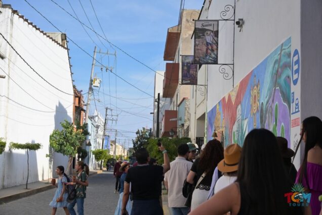 Tour group walking along a colorful mural-lined street in Tequila, Jalisco.